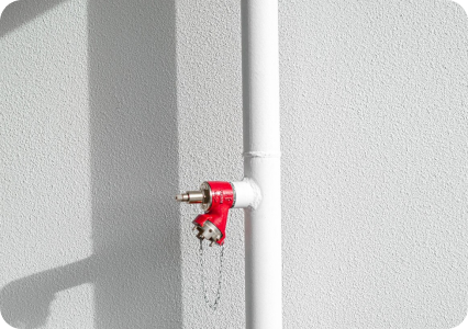Fire sprinkler system connection mounted on a wall with red outlet fittings