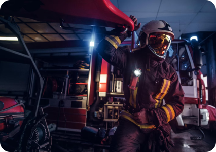 Firefighter in protective gear standing beside a fire truck during an emergency response