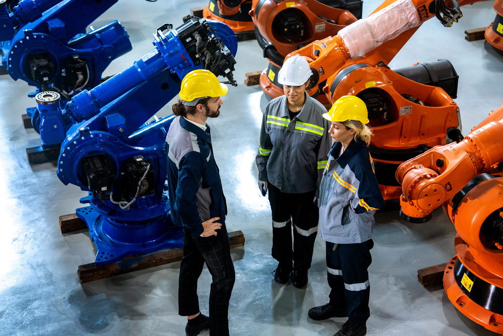 Male engineer talking to a group of men and women team meeting discuss maintenance plan of robotic arm stock in warehouse